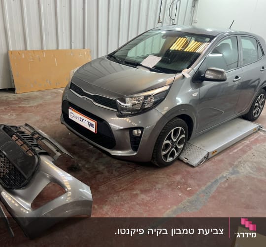 רכב אפור עם פגוש מנותק במוסך תיקונים
